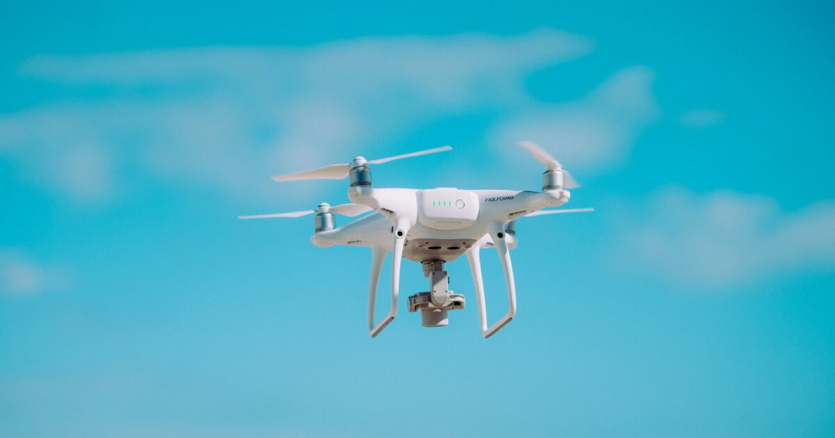 雲のある青空に浮かぶ白いドローン