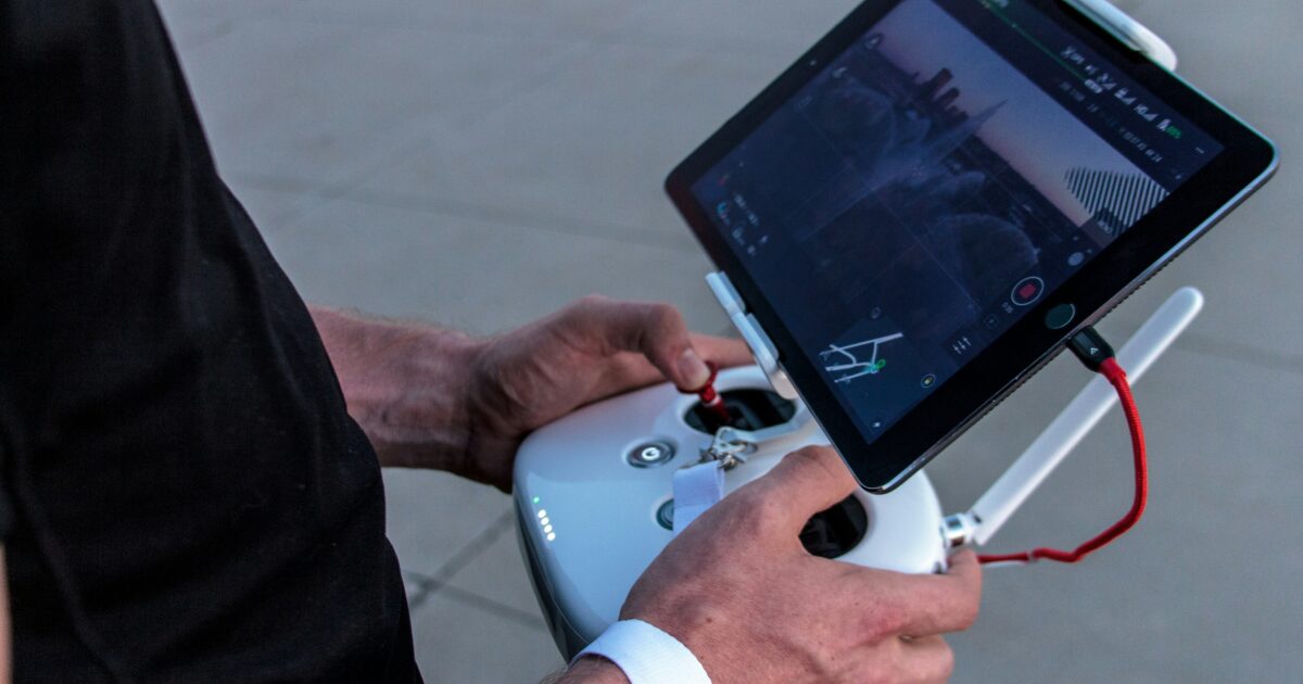 タブレット付き送信機でドローンを操作する手元