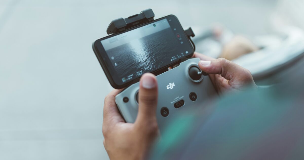 送信機とスマートフォンでドローンを操作する手元