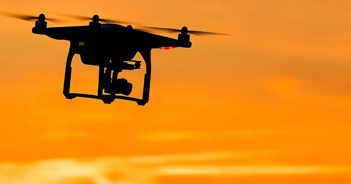 夕焼け空にシルエットで浮かぶドローン