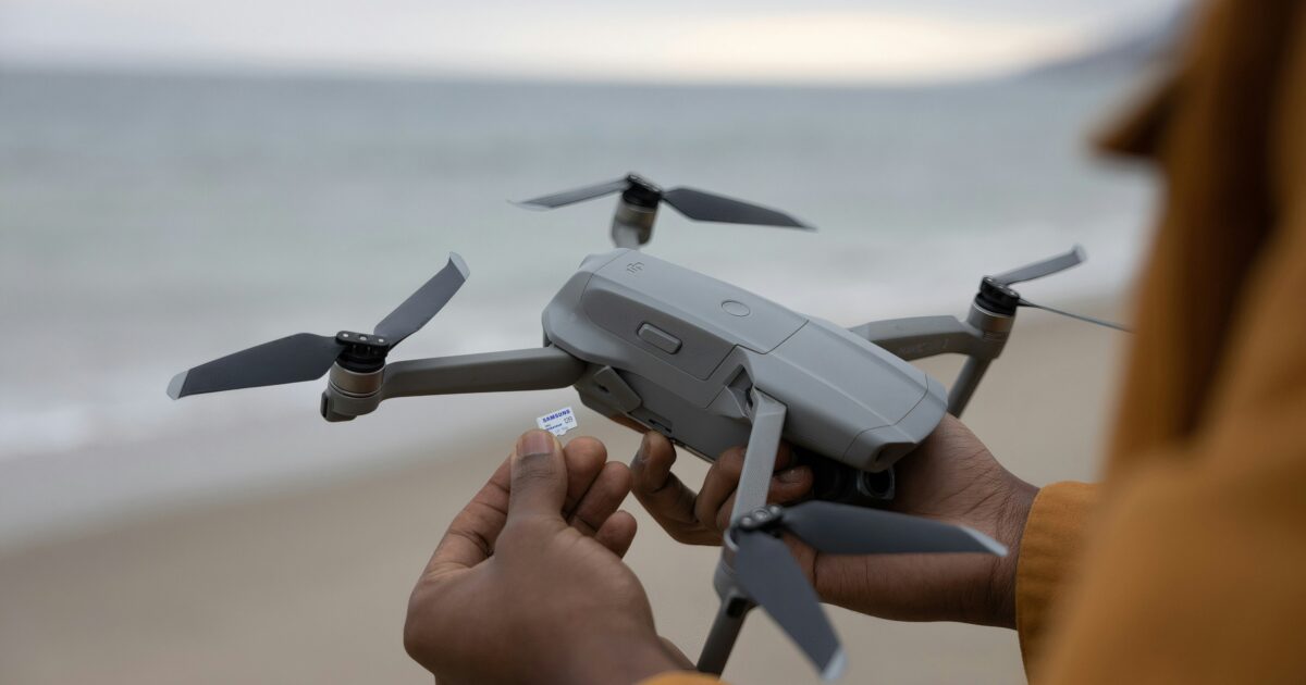 浜辺でドローンにメモリーカードを装着する様子