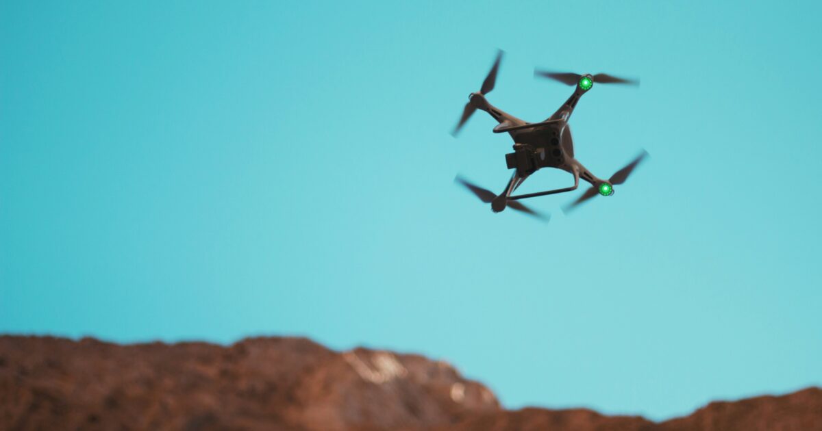 山岳地帯の上空を飛行する緑色LED付きドローン