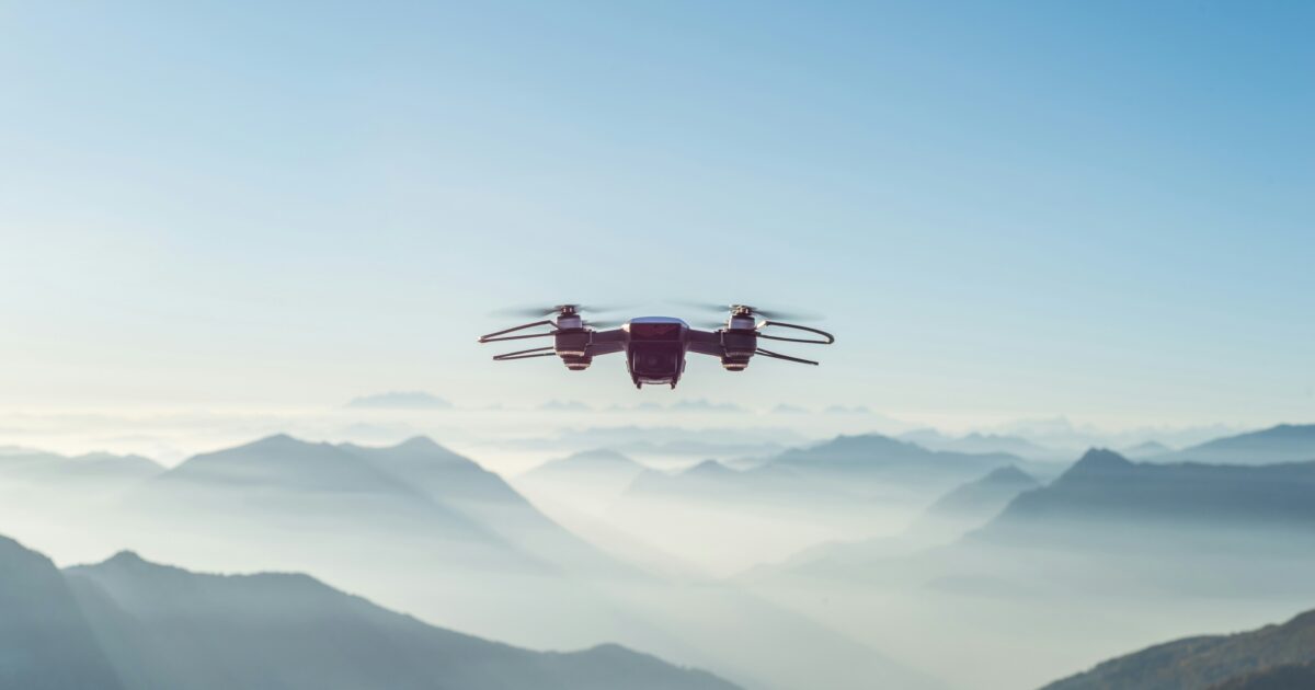 山岳地帯の上空を飛ぶ小型ドローン