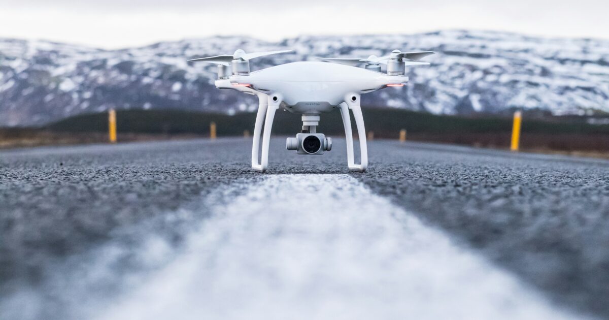 雪山を背景に道路上に置かれた白いドローン